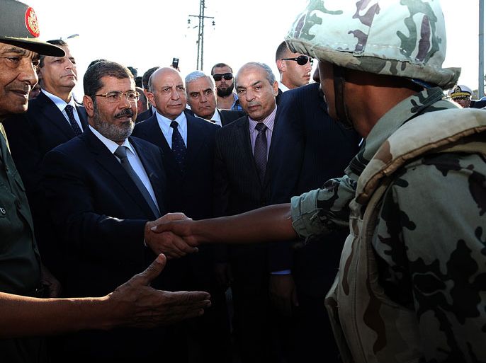 This hand out picture made available by the Egyptian presidency on August 6, 2012, shows Egyptian President Mohamed Morsi (C) and Egyptian Defence Minister and Field Marshall Hussein Tantawi (L) as they visit soldiers in al-Arish, in the northern Sinai. Egypt's army vowed to "avenge" the killing of 16 troops by gunmen near the Israeli border, as President Mohamed Morsi ordered security forces to take full control of the Sinai Peninsula. In yesterday's attack, 35 gunmen in Bedouin clothing opened fire on the troops before crossing into the Jewish state in an armoured vehicle, Egyptian officials said. Israel said five gunmen were killed on its side. AFP PHOTO/EGYPTIAN PRESIDENCY == RESTRICTED TO EDITORIAL USE - MANDATORY CREDIT "AFP PHOTO/EGYPTIAN PRESIDENCY" - NO MARKETING NO ADVERTISING CAMPAIGNS - DISTRIBUTED AS A SERVICE TO CLIENTS ==