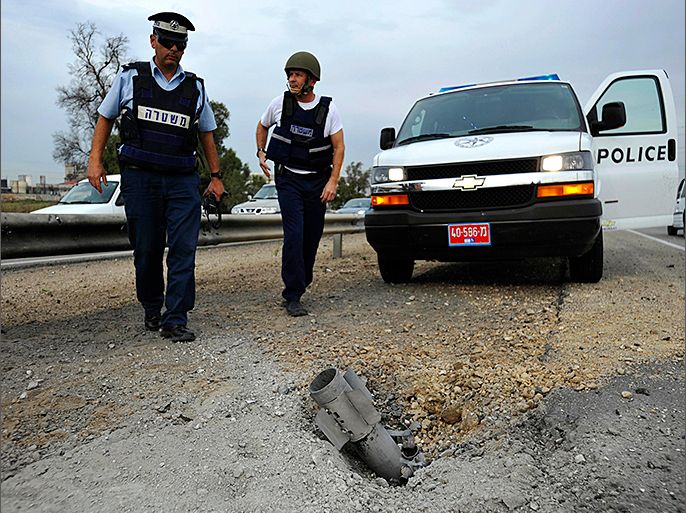 Israeli police officers walk behind the remains of a rocket fired by Palestinian militants in Gaza after it landed near the port city of Ashdod, in this January 16, 2009 file photo. Israeli sources say there is evidence Egypt's north Sinai region is becoming not only a rallying point for jihadist gunmen but a firing range for Gaza's indefatigable rocket builders, seeking ever greater range and accuracy for mainly homemade weapons. It was soon after the 2011 revolt in Egypt toppled President Hosni Mubarak that Israeli rocket radars began to spot unusual launches from the Palestinian territory, which Israel keeps under a land, sea and air cordon. Normally they streaked towards Israeli border towns, or north towards coastal cities. But now some were aimed at the empty desert wastes of Sinai. REUTERS/Amir Cohen/Files (ISRAEL - Tags: POLITICS CIVIL UNREST CONFLICT CRIME LAW)
