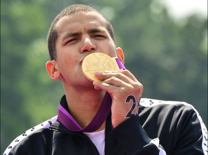 London, Greater London, UNITED KINGDOM : Tunisia's Oussama Mellouli (C) kisses his gold medal after winning the men's 10km open water swimming marathon at the London 2012 Olympic Games at Hyde Park in London, on August 10, 2012. Mellouli claimed victory to become the first person to win Olympic titles in both pool and open water races. AFP PHOTO / LUIS ACOSTA
