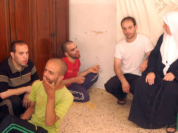 ام حسام تجلس بين ابنائها الاربعة الذين يعانون اعاقات صعبة ومختلفة- الجزيرة نت1