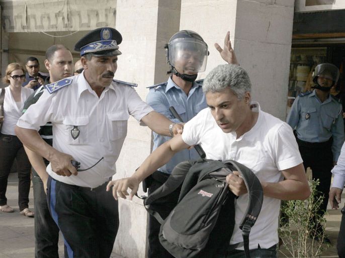 AFP journalist Omar Brouksy is grabbed by police during a protest outside parliament on August 22, 2012, where activists had gathered to call for the abolition of a ceremony of loyalty to the king. Dozens of activists, most of them from the February 20 reform movement, demonstrated on the main boulevard in Rabat, chanting "Dignity, freedom and social justice!" AFP PHOTO /ABDELHAK SENNA