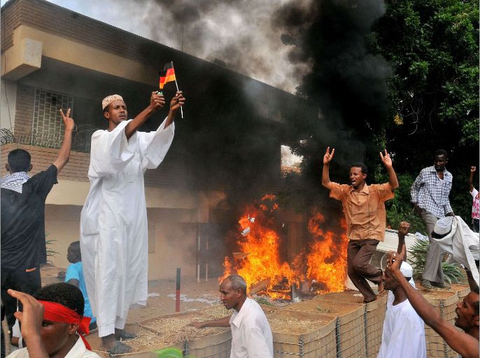 A Sudanese demonstrator burns a German flag as others shout slogans after torching the German embassy in Khartoum during a protest against a low-budget film mocking Islam on September 14, 2012. Around 5,000 protesters in the Sudanese capital angry over the amateur anti-Islam film stormed the embassies of Britain and Germany, which was torched and badly damaged. AFP PHOTO / ASHRAF SHAZLY
