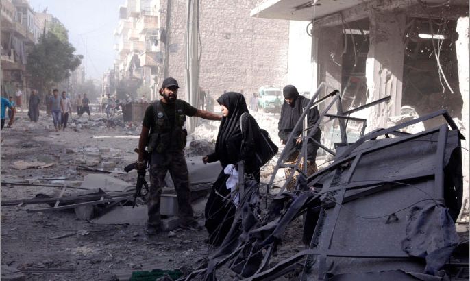 A member of the Free Syrian Army helps women as they leave a shelled building in Aleppo's district of al-Shaar September 16, 2012. REUTERS/Zain Karam (SYRIA - Tags: CONFLICT)