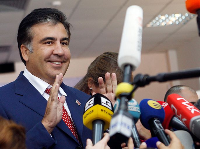 r : Georgia's President Mikheil Saakashvili (L) talks to the media at a polling station during the parliamentary election in Tbilisi October 1, 2012. Georgians elect a parliament on Monday with tension high after a prison abuse scandal that has turned the vote into the biggest test of President Mikheil Saakashvili's grip on the Caucasus Mountain nation in nearly a decade in power. REUTERS/David Mdzinarishvili (GEORGIA - Tags: POLITICS ELECTIONS)
