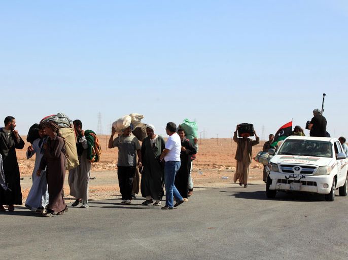 Mainly foreign workers flee their homes in Bani Walid, one of the final bastions of Moamer Kadhafi's regime, on October 21, 2012. Clashes on October 20, between pro-government forces and fighters described by authorities as criminals and loyalists of Kadhafi's ousted regime killed at least 26 people and wounded more than 200, according to an AFP tally. AFP PHOTO/MAHMUD TURKIA