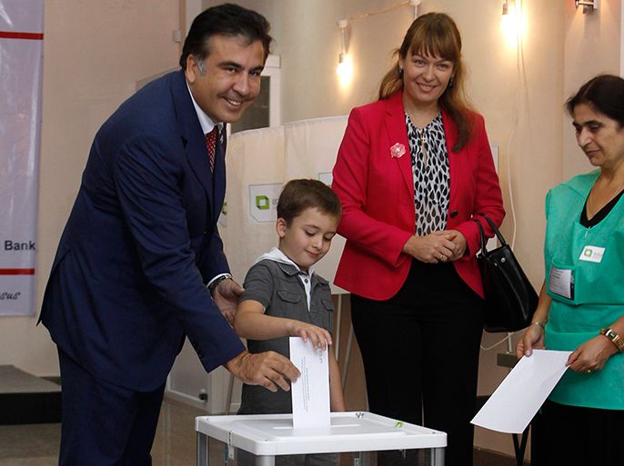 r : Georgia's President Mikheil Saakashvili (L), accompanied by his wife Sandra Roelofs (2nd R) and son Nikoloz (2nd L), casts his vote during a parliamentary election at a polling station in Tbilisi October 1, 2012. Georgians elect a parliament on Monday with tension high after a prison abuse scandal that has turned the vote into the biggest test of Saakashvili's grip on the Caucasus Mountain nation in nearly a decade in power. REUTERS/David Mdzinarishvili (GEORGIA - Tags: POLITICS ELECTIONS)