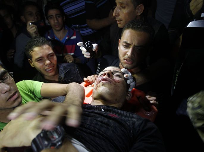 Palestinian men grieve over the body of Ahmad al-Dradsawi, 20, as he is carried into the al-Shifa hospital in Gaza City after he was killed in Israeli shelling as clashes erupted along the border on November 10, 2012. Israeli artillery fire killed one Palestinian and wounded more than 20 others, some of them seriously, spokesman Yahya Khader of the Hamas government's emergency services in the Gaza Strip said. AFP PHOTO/MOHAMMED ABED