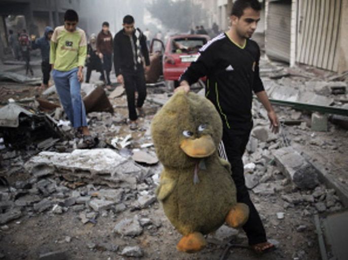 MLO28 - GAZA CITY, GAZA STRIP, - : A Palestinian man carries a stuffed toy in a street littered with debris after a Israeli air raid on a nearby sporting centre in Gaza City on November 19, 2012. Israeli air strikes on Sunday killed 31 Palestinians in the bloodiest day so far of its air campaign on the Gaza Strip, as diplomatic efforts to broker a truce intensified. AFP PHOTO/MARCO LONGARI