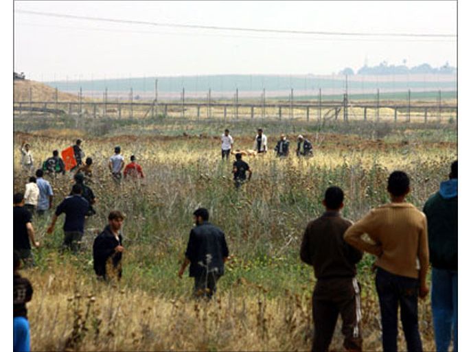 afp : a crowd of palestinian onlookers watch as medics carry the body of a militant (back-c) killed by israeli gunfire at the border fence east of gaza city on april 16, 2010. military (الفرنسية)