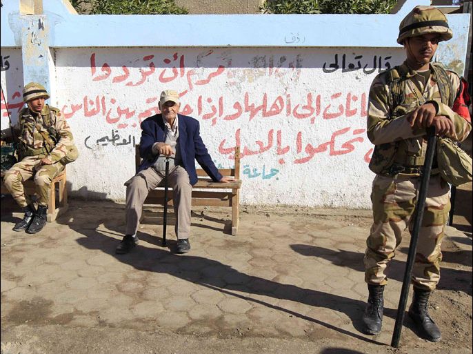 Soldiers keep guard near a man sitting outside a polling centre during the final stage of a referendum on Egypt's new constitution in El Arbeen district of Suez, 120 km (75 miles) away from Cairo, December 22, 2012. Egyptians voted on a constitution drafted by Islamists on Saturday in a second round of balloting expected to approve the charter that opponents say will create deeper turmoil in Egypt, REUTERS/Mohamed Abd El Ghany (EGYPT - Tags: POLITICS ELECTIONS MILITARY)