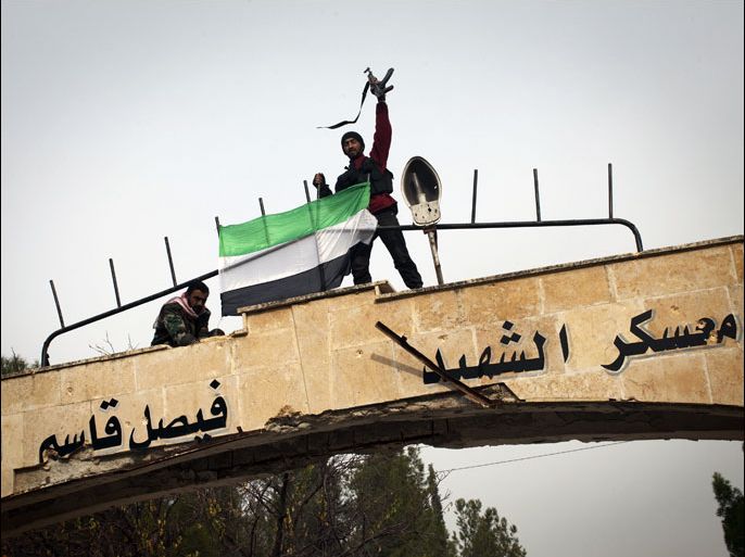 Syrian rebels celebrate on top of the gate of the al-Moshat infantry academy after seizing it from regime forces in the town of Fafeen just north of the city of Aleppo on December 16, 2012. Syrian troops withdrew from the key infantry academy, after rebels seized most of the complex the previous day, the Syrian Observatory for Human Rights said. At least 24 rebel fighters, including Abu Furat, a top rebel commander in Aleppo province, were killed in the battle for the academy along with 20 regime troops, the Britain-based watchdog said. AFP PHOTO / JM LOPEZ