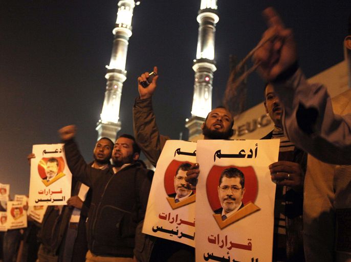 Muslim Brotherhood members and supporters of Egyptian President Mohamed Morsi shout slogans as they hold banners bearing his portrait and reading in Arabic: "support the decisions of the President" during a demonstration outside a mosque in Cairo on December 9, 2012. Egypt's main opposition parties were to meet to decide whether to keep up street protests against Morsi after the Islamist leader made a key concession in the crisis dividing the nation. AFP PHOTO/PATRICK BAZ