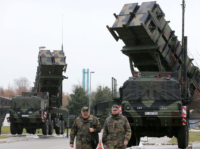 afp : (FILES) - Picture taken on December 4, 2012 shows soldiers of the Air Defence Missile Squadron 2 walking past Patriot missile launchers in the background in Bad Suelze, northern Germany. German parliament is set to vote on on December 14, 2012 on the deployment of Patriot missiles and soldiers on Turkey's volatile border with war-ravaged Syria. AFP PHOTO / BERND WUSTNECK GERMANY OUT