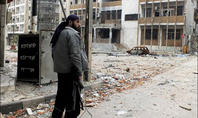 A Free Syrian Army Fighter carries his weapon as he stands on a damaged street in Homs, December 19, 2012. Picture taken December 19, 2012. REUTERS/Yazan Homsy (SYRIA - Tags: CONFLICT POLITICS TPX IMAGES OF THE DAY)
