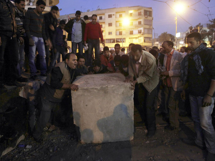 ‪المتظاهرون يزيلون جدارا إسمنتيا للوصول إلى القصر‬ (رويترز)