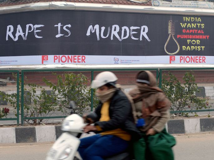 Female commuters ride a scooter past a billboard, calling for capital punishment against rape, in New Delhi on December 27, 2012. An Indian student who was left fighting for her life after being brutally gang raped on a bus in New Delhi arrived December 27 in Singapore for treatment at a leading hospital. The attack sparked a wave of protests across India in which a policeman died and more than 100 police and protestors were injured. AFP PHOTO/RAVEENDRAN