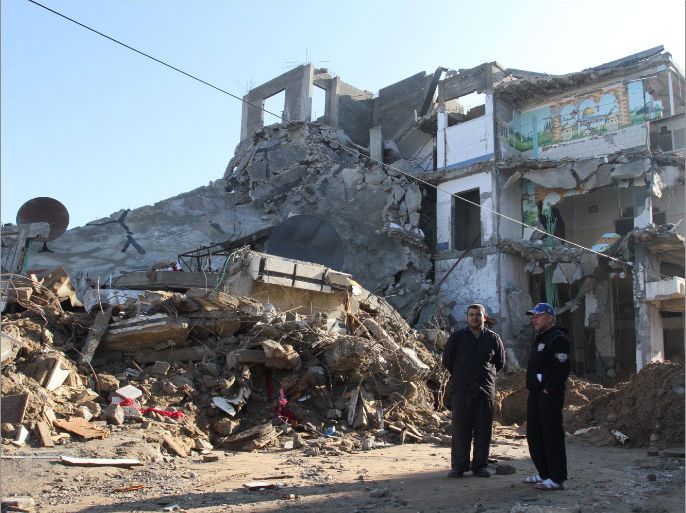 مواطنان أمام منزلهما بمدينة غزة الذي دمرته غارة إسرائيلية في عدوان الأيام الثمانية