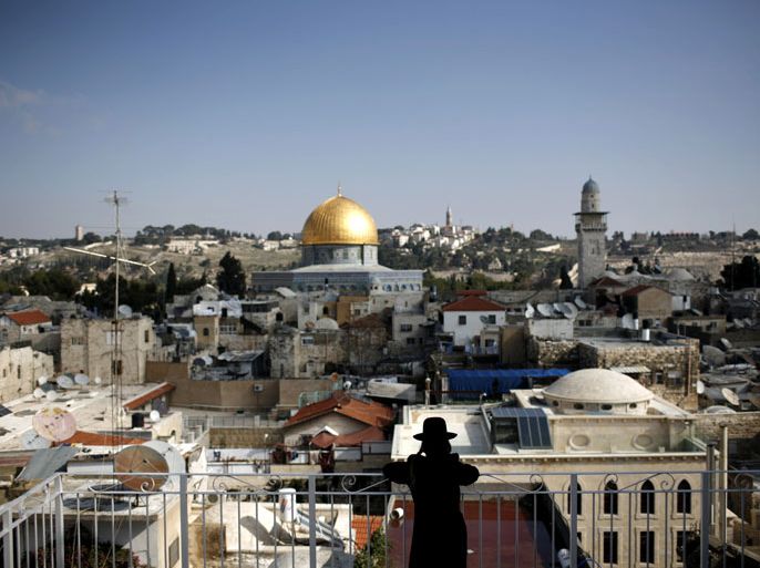 epa03060739 An Ultra Orthodox Jewish man stands on the roof of a Yeshiva with the the Dome of the Rock in the background in the Muslim Quarter, Jerusalem, 15 January 2012. EPA/ABIR SULTAN