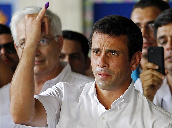 Venezuela's opposition presidential candidate Henrique Capriles holds up his ink-stained finger as proof of having voted in the presidential election pitting him against President Hugo Chavez, in Caracas October 7, 2012. Venezuelan President Hugo Chavez faces the toughest election of his 14-year rule on Sunday in a vote pitting his charisma and oil-financed largesse against fresh-faced challenger Henrique Capriles' promise of jobs, safer streets and an end to cronyism. REUTERS/Carlos Garcia Rawlins (VENEZUELA - Tags: POLITICS ELECTIONS)