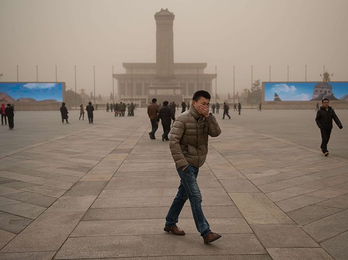 A man covers his face as he walks on Tiananmen Square during a sand storm in heavily polluted weather in Beijing on February 28, 2013. Beijing residents were urged to stay indoors as pollution levels soared before a sandstorm brought further misery to China's capital. AFP PHOTO / Ed Jones