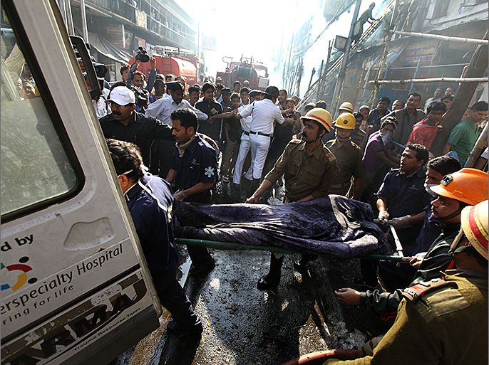 epa03602257 Indian rescue workers recover a victim's dead body after a fire at a market in Calcutta, India, 27 February 2013. At least 18 people were killed when a fire broke out in a multi-storey market in Calcutta on 27 February. The paper and plastics market was illegally constructed and unauthorized, state Fire Minister Javed Khan said. EPA/PIYAL ADHIKARY