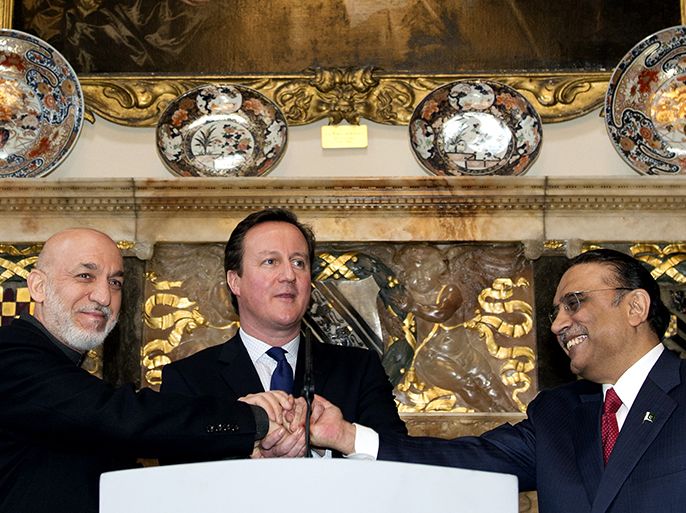 Britain's Prime Minister David Cameron (C) shakes hands with Afghan President Hamid Karzai (L) and Pakistani President Asif Ali Zardari (R) at Chequers, the Prime Minister's official country residence, near Aylesbury in Buckinghamshire, west of London, on February 4, 2013. Karzai and Zardari vowed to achieve a peace settlement for Afghanistan within six months, after the talks hosted by Britain. AFP PHOTO / POOL/ ADRIAN DENNIS