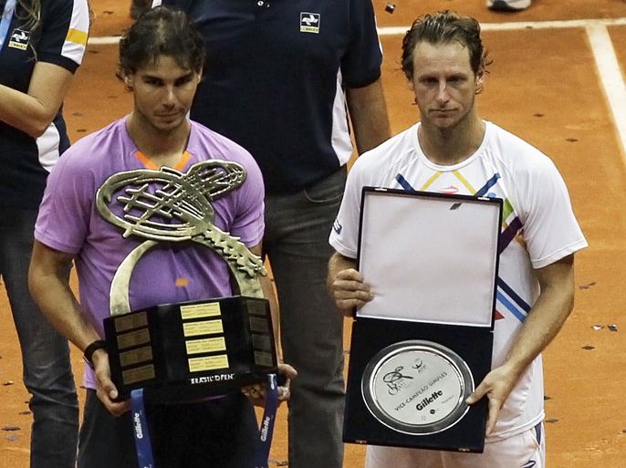 Rafael Nadal (L) of Spain poses with his trophy after winning the men's singles final against David Nalbandian of Argentina at the Brazil Open tennis tournament in Sao Paulo February 17, 2013. REUTERS/Nacho Doce (BRAZIL - Tags: SPORT TENNIS)