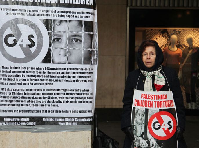 متضامنة ترفع لافتة كتب عليها تعذيب الاطفال الفلسطينيين وإشارة لوقف عمل الشركة