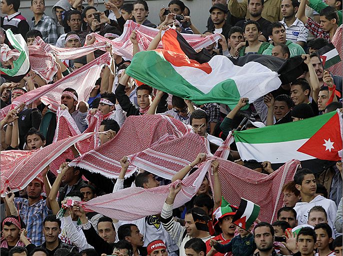 Jordanian fans wave their national flag and traditional Arab Keffiyeh scarves as their cheer on their team prior to the start of their FIFA World Cup Group B Asian qualifiers round four football match against Japan, in Amman, on March 26, 2013. AFP PHOTO/KHALIL MAZRAAWI