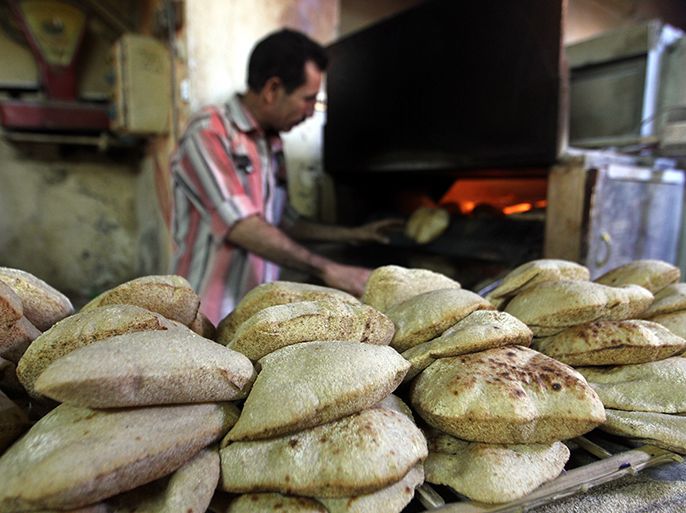 epa03632656 An Egyptian man prepares bread in a bakery iin Cairo, Egypt, 20 March 2013. According to local media reports hundreds of bakery owners in Egypt blocked entrances to the supply ministry to protest against a new government plan to raise the price of flour used to produce state subsidized. EPA/KHALED ELFIQI