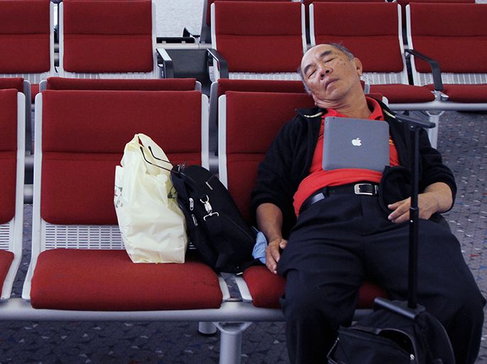 epa03646562 A picture made available 01 April 2013 shows a passenger catching up with some sleep with his computer resting on his chest, at an airport electronic charging point for appliances, in the international terminal of Hong Kong airport, China, 31 March 2013. Charging appliances and charging travelers own batteries on exhausting travel schedules, present international airports with logistical challenges. EPA/BARBARA WALTON
