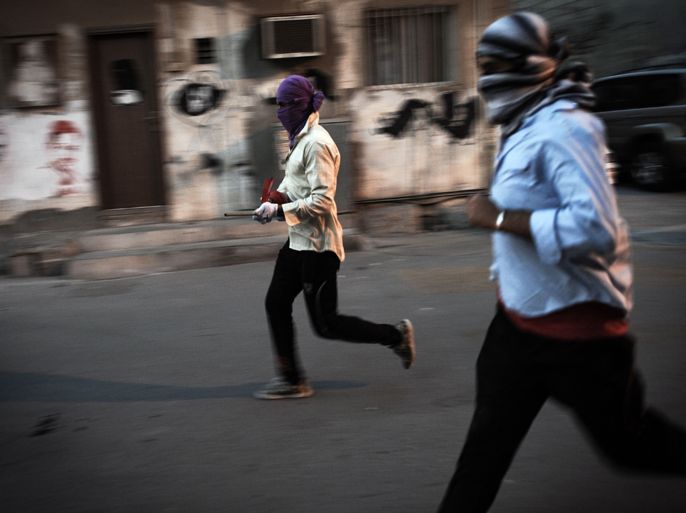 MAS07 - Sanabis, -, BAHRAIN : Bahraini demonstrators run for cover during clashes with riot police following a protest against the Formula One Grand Prix on April 21, 2013 in the village of Sanabis, west of Manama. AFP PHOTO/