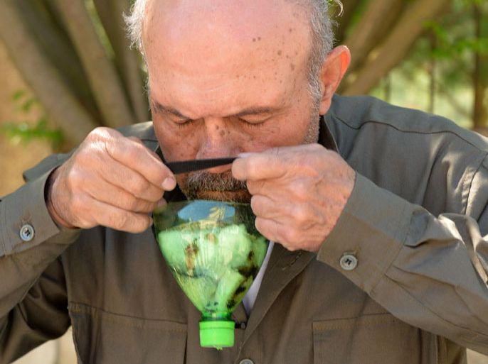 A picture taken on April 26, 2013 shows Abu Tarek, a 74-year-old retired army officer, trying on a homemade gas-mask assembled using a plastic bottle, coal, cotton, gauze, cola, and cardboard, for protection against chemical weapons, in Syria's northern Latakia province. The emerging allegations of likely chemical attacks by Assad’s regime have stirred outrage around the world,