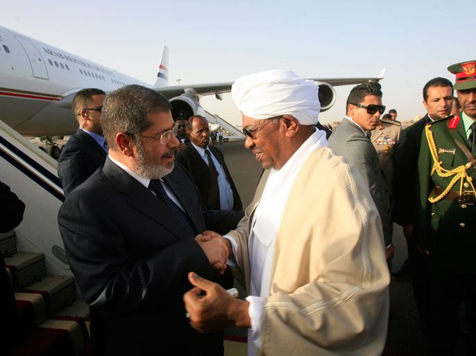 Sudanese President Omar al-Bashir (R) greets Egyptian President Mohammed Morsi upon his arrival in Khartoum on April 4, 2013. Morsi arrived in neighbouring Sudan to push economic and other ties on a visit Khartoum calls "historic" but which comes nearly a year after Morsi's election. AFP PHOTO/ASHRAF SHAZLY
