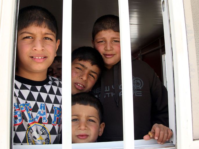 AMM23 - Zarqa, -, JORDAN : Syrian refugee children look out the window of a portacabin at the newly built UAE funded Mrigb al-Fuhud refugee camp, 20 kilometres east of the Jordanian city of Zarqa, on April 15, 2013. The seven-million-dinar ($9.8-million) camp which has 750 caravans, a hospital, and a school and can take up to 5,500 people, was paid for by the United Arab Emirates. AFP PHOTO/STR
