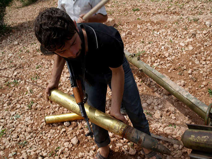 ‪أحد مقاتلي الجيش الحر يجهز الصواريخ لقصف مواقع للنظام‬ (رويترز)