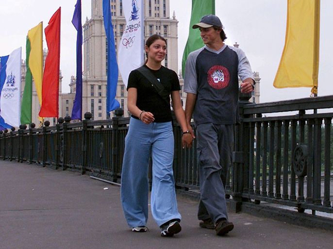 MOSCOW, RUSSIAN FEDERATION: A young couple walk accross a bridge in Moscow, decorated with colourfull flags with olympic symbols, as the 112th session of the International Olympic Committee started its work today in Moscow 09 July 2001.