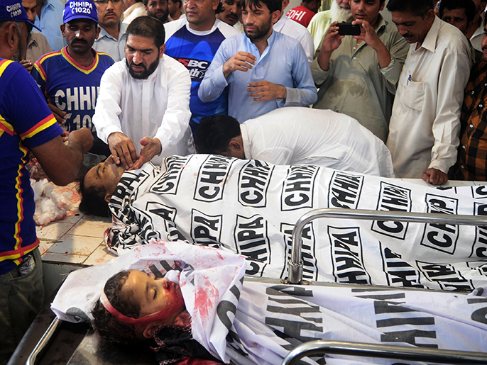‪جثتا صديق الزمان عمران ونجله بعد استهدافهما في كراتشي‬ (الفرنسية)