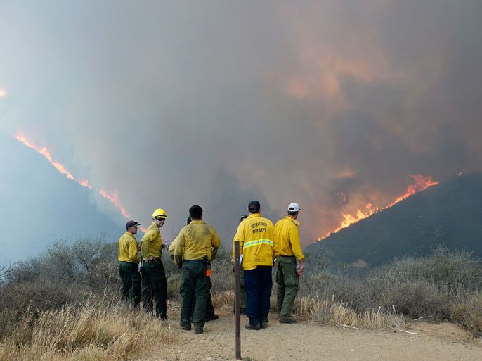 California, UNITED STATES : NEWBURY PARK, CA - MAY 03: Firefighters look on as wildfire charges back up from Sycamore Canyon inside Pt. Mugu State Park caused by changing winds on May 3, 2013 in Newbury Park, California. Hundreds of firefighters are battling wind and dry conditions with over 10,000 acres already burned