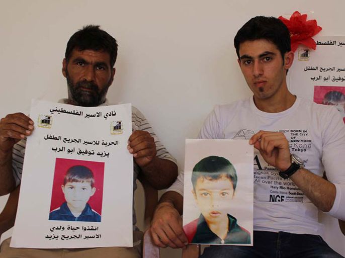 ذوو الطفلان ابو الرب يحملان صورتهما وقد وصفا حالتهما داخل سجون الاحتلال بالصعبة- الجزيرة نت