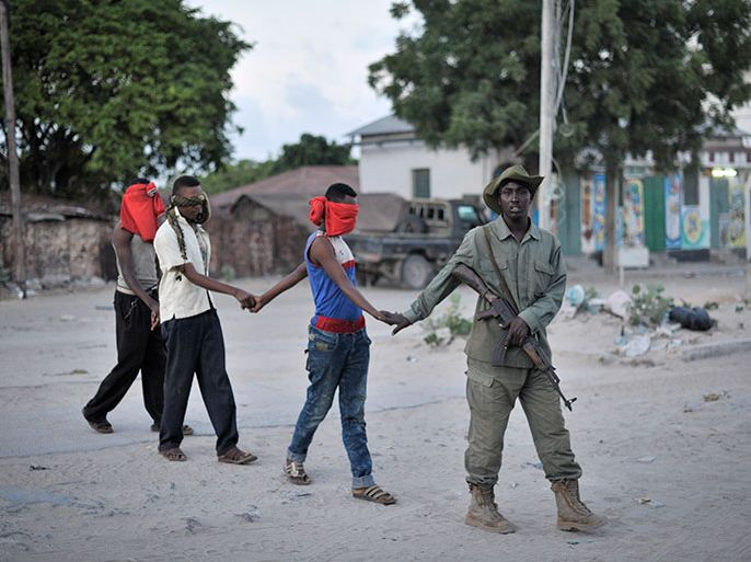 This handout photo released by the AU-UN 1ST shows three young men led by a member of the Somali Police Force to a holding area with other civilians during an operation aimed at improving security in Mogadishu, Somalia, on May 21. AMISOM, in support of the Somali Police Force, last night cordoned off one square kilometer in the Wardhiigleey district of Mogadishu in an attempt to weed out members of the extremist group, al Shabaab. Many of the area's young men were temporarily detained by the SPF and then screened in order to determine whether they had any links to the group. AU UN IST PHOTO/ TOBIN JONES