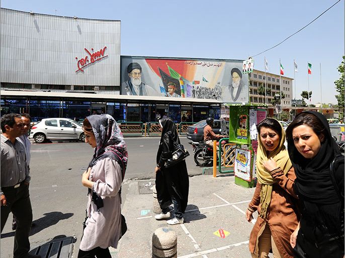epa03742985 Iranians walk on a street of Tehran, with a huge billboard showing Iranian Supreme Leader Ayatollah Khamenei (L) and Iranian late Supreme Leader Ruhollah Khomeini (R) pictured in the background, Tehran, Iran, 13 June 2013. Iran will hold presidential elections on 14 June 2013. EPA/ABEDIN TAHERKENAREH