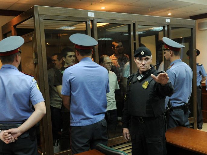Defendants gesture inside a glass-walled cage known as an "aquarium" in Moscow's City Court on June 6, 2013. Twelve Russians went on trial in Moscow today accused of violence at a rally on the eve of President Vladimir Putin's inauguration last year, in a case condemned by critics as a show trial aimed at suffocating dissent. The participants are being tried over what the Kremlin calls "mass riots" on Bolotnaya Square in central Moscow during a peaceful rally on May 6, 2012 which suddenly descended into violence one day before Putin was inaugurated for his term presidential term