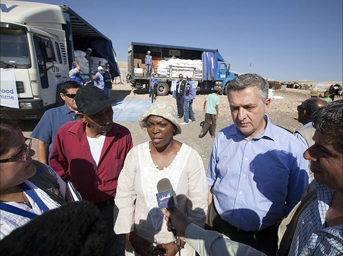 World Food Programme Executive Director Ertharin Cousin (C), speaks to journalists as worker distribute food at the West Bank Bedouin camp of Khan al-Ahmar on June 21, 2013. Food insecurity is on the rise in the West Bank and is jeopardising stability, the head of the UN's World Food Programme said on a visit to the Palestinian territory. AFP PHOTO/AHMAD GHARABLI