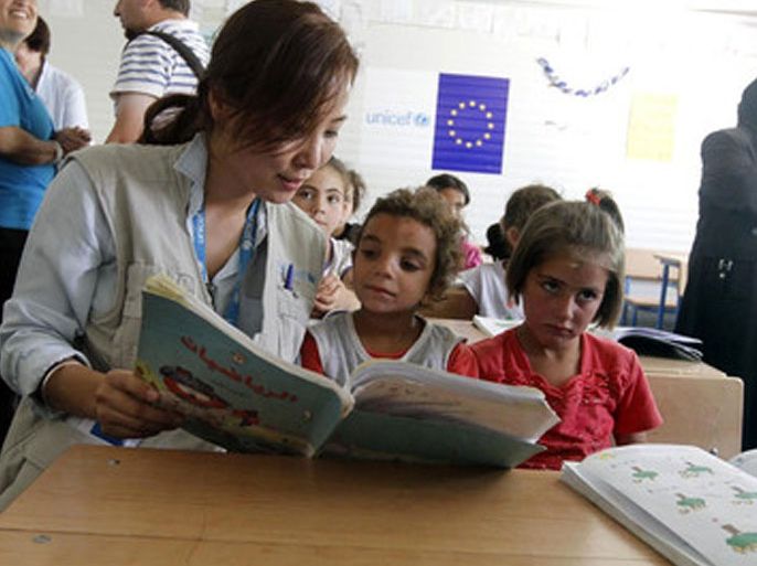 epa03730777 A UNICEF official (L) reads for Syrian refugee students at a school for Syrian refugees at Zattari camp near the city of Mafraq, Jordan, 04 June 2013. European Union Commissioner for Enlargement and European Neighborhood Policy Stefan Fule inaugurated the second school financed by the European Commission through UNICEF at the refugee camp. Commissioner Fule on 03 June announced an additional 50 million Euros of assistance to Jordan to alleviate the impact of the high influx of refugees from Syria, bringing the total amount of financial assistance provided by the European Commission to Jordan in relation to the Syrian crisis to 137 million euros since its outbreak