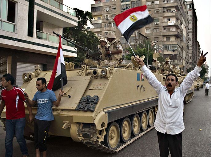 Egyptians salute Army tanks upon their deployment on a street leading to Cairo University on July 3, 2013. A top aide to Egypt's President Mohamed Morsi slammed what he called a "military coup" as an army ultimatum passed and the security forces slapped a travel ban on the Islamist leader. AFP PHOTO/KHALED DESOUKI