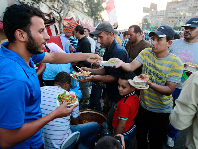 متطوعون يوزعون وجبة الإفطار على معتصمي رابعة العدوية (رويترز)