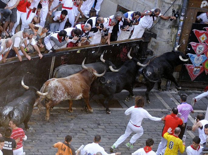 Participants run in front of Miura's bulls during the last bull run of the San Fermin Festival in Pamplona, northern Spain, on July 14, 2013. AFP PHOTO/ ANDER GILLENEA