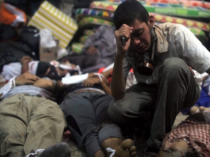 A young man mourns next to the bodies of protesters killed during the clearing of one of the two sit-ins of ousted president Morsi supporters, at the field hospital, near Rabaa Adawiya mosque, Cairo, Egypt, 14 August 2013. According to local media reports, one soldier and dozens of protesters were killed and about 200 others arrested as Egyptian security forces began clearing islamist protest camps in the capital Cairo on 14 August. The military-backed government described the protest camps as violent and unlawful. The biggest sit-ins are in north-eastern Cairo and south of the capital.