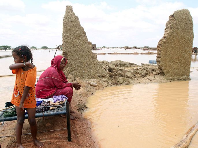 A Sudanese women sits next to her house in a flooded street on the outskirts of the capital Khartoum on August 10, 2013. Drainage is poor in the capital, where even a little rain can cause flooding but this year's water surge was unusually severe. AFP PHOTO / ASHRAF SHAZLY